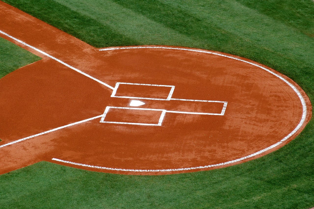 services-01 A top-down view of a baseball field's home plate area on a sunny day.
